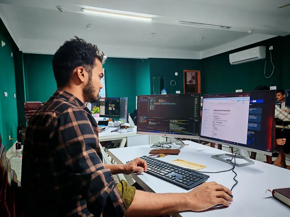 Developer writing code across two monitors in a modern office