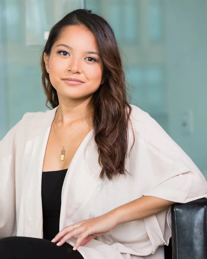 Confident businesswoman seated in a bright, glass-walled office