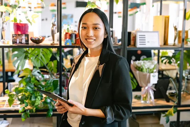 Asian shop owner holding a tablet in her flower and lifestyle store