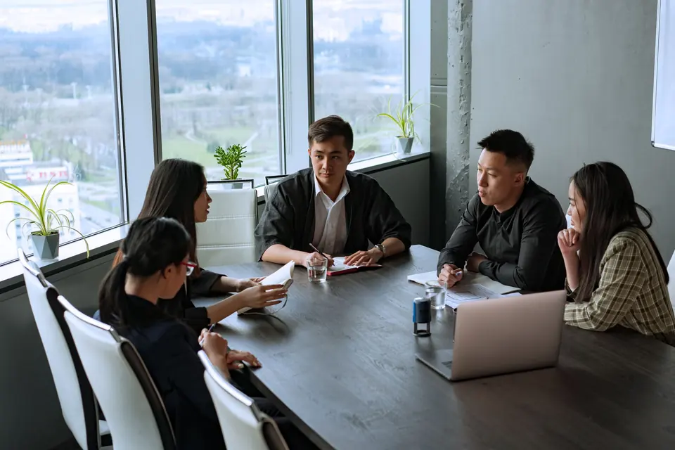 Asian business team meeting around a table in a high-rise office
